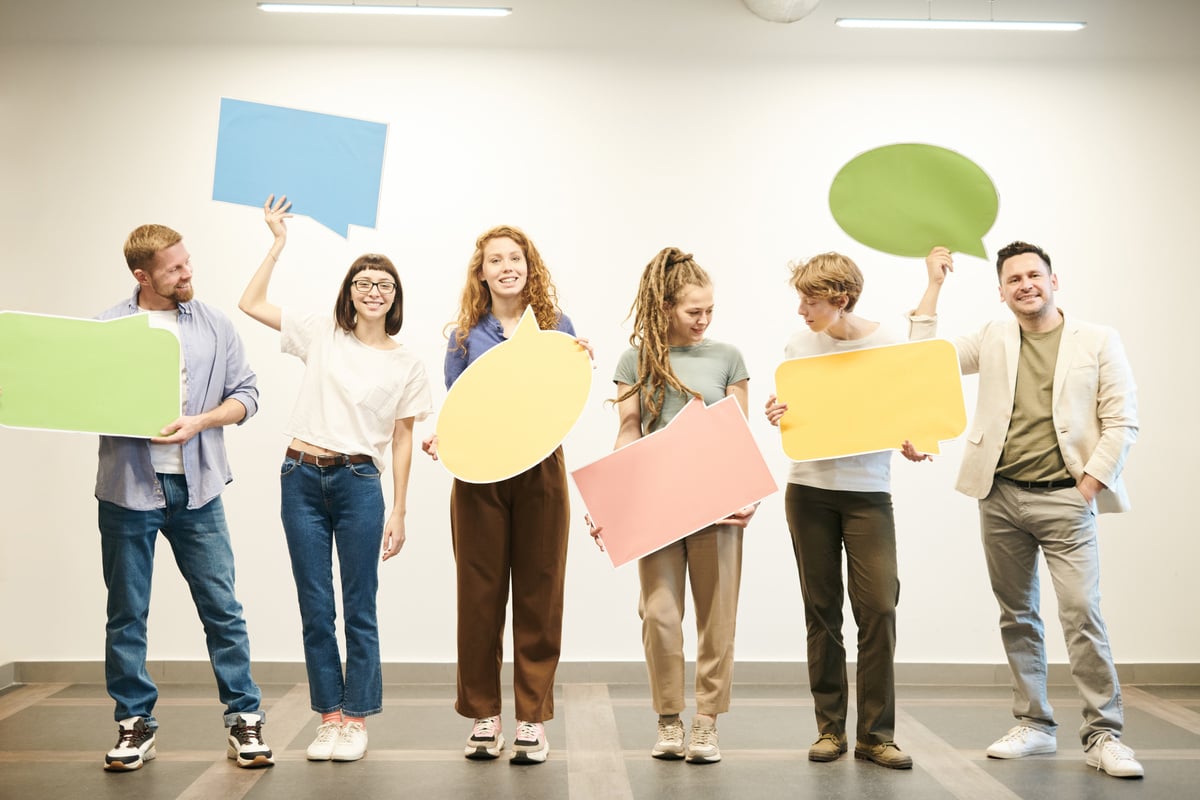 Diverse group of men and women holding up an empty speech bubble sign